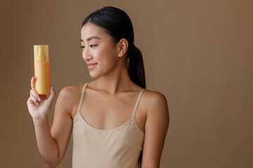 Brunette young woman holding bottle of hair spray