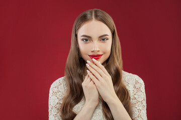 Pretty smiling woman with makeup and manicured nails on her hands on red background