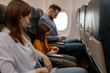 Obraz premium Parents and daughter traveling together on passenger aircraft