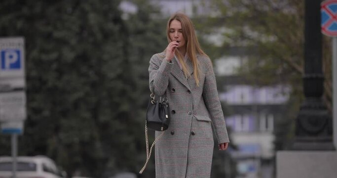 Woman smoking electronic cigarette, vape walking in the city