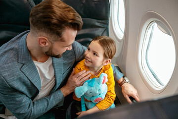Man with daughter sitting by the window in airplane