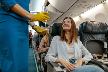 Flight attendant offering champagne to woman in airplane