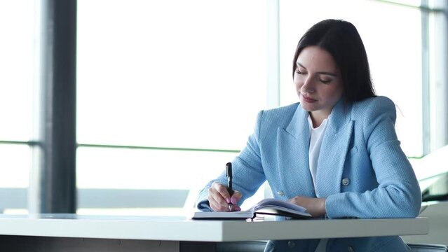 Business woman working in office and writing in notebook