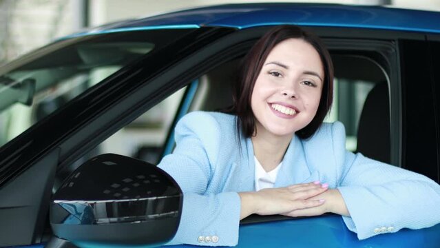 Woman sitting in car and smiling into camera 
