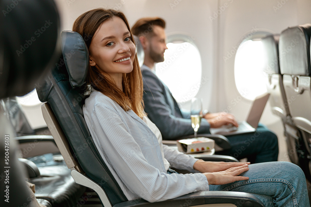 Wall mural Joyful woman sitting in passenger chair in airplane