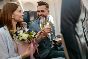 Happy couple toasting with champagne in passenger plane