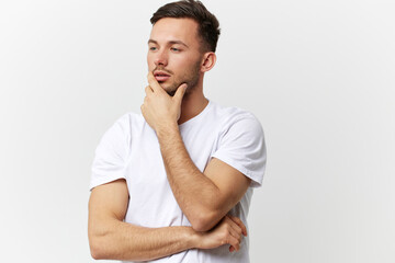 Fototapeta na wymiar Pensive thoughtful sad tanned handsome man in basic t-shirt touch chin look aside posing isolated on over white studio background. Copy space Banner Mockup. People emotions Lifestyle concept
