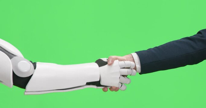 Close up of businessman and modern robot shaking hands over chroma key studio background. Concept of people, artificial intelligence and cooperation.