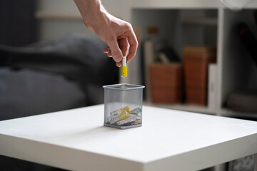 hand holds the AA electric battery and throw it in the trash bin as the symbol of recycle and reuse