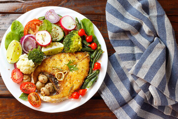 Ketogenic or paleo diet dish, grilled fish and vegetables on rustic wooden table. Low carb food, healthy eating