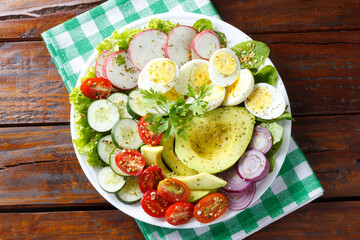 Ketogenic or paleo diet plate, avocado salad and eggs on rustic wooden table. Low carb food, healthy eating