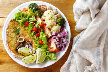 Ketogenic or paleo diet dish, grilled fish and vegetables on rustic wooden table. Low carb food, healthy eating