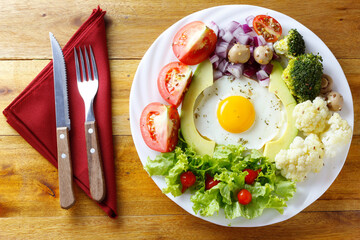 Ketogenic or paleo diet plate, avocado salad and eggs on rustic wooden table. Low carb food, healthy eating