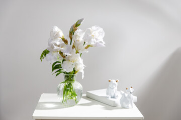 A vase with white iris, pieces of paper, a figurine with a fox. Scandinavian style.