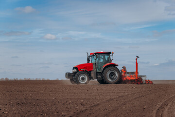 Spring sowing season. Farmer with a tractor sows corn seeds on his field. Planting corn with trailed planter. Farming seeding. The concept of agriculture and agricultural machinery.
