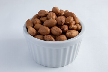 Nutritious and natural raw peanuts, shelled and still with the skin in a small ceramic pot.