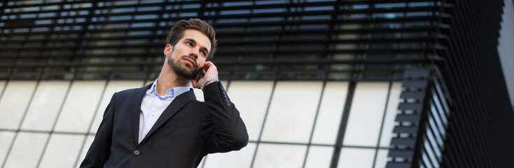	
Young businessman talking on the phone in front of corporate office building