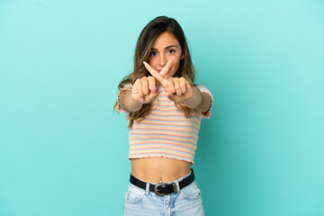 Fototapeta premium Young woman over isolated blue background making stop gesture with her hand to stop an act