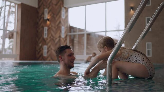 dad is teaching his little daughter to swim in pool, happy childhood moments