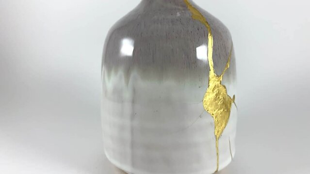 Kintsugi, Gold cracks slow motion detail video, broken vase, Japanese technique. Isolated closeup.