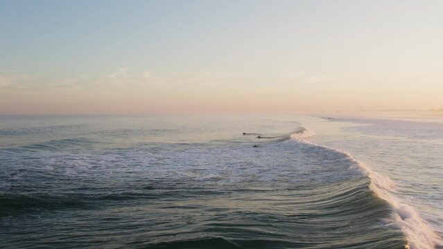 Drone footage of surfers at golden hour
