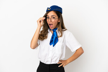 Airplane stewardess over isolated white background with glasses and surprised