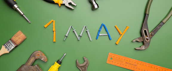 International Workers' Solidarity Day, 1 May concept. Different construction tools on green...