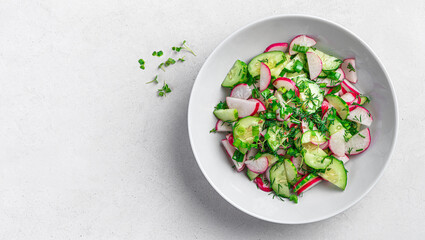 Salad with radish, cucumber, fresh herbs and flax seeds on a gray background with space to copy.