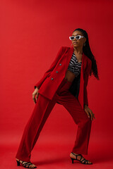 Elegant fashionable Black woman wearing classic red suit with blazer and trousers, zebra print top,...