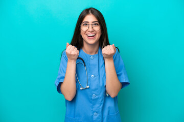 Young nurse caucasian woman isolated on blue background celebrating a victory in winner position