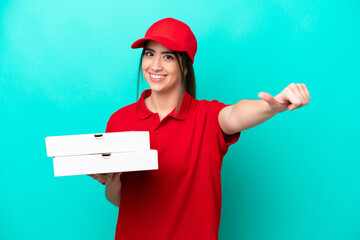 Pizza delivery woman with work uniform picking up pizza boxes isolated on blue background giving a...