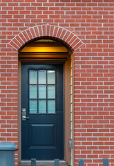 Red brick wall with nice brown door. Exteriror of a house. Entrance of a nice single family house.