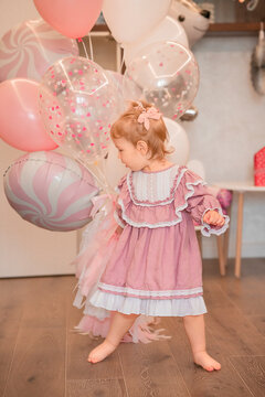 Cute baby girl dancing with bunch of pink balloons. View of happy child with balloons.