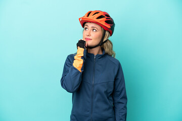 Young cyclist woman isolated on blue background and looking up