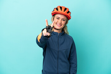 Young cyclist woman isolated on blue background smiling and showing victory sign