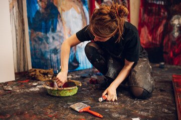 Woman artist mixing colors to paint picture with paintbrush