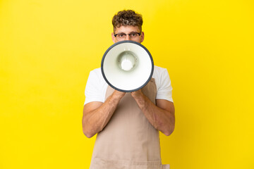 Restaurant waiter blonde man isolated on yellow background shouting through a megaphone
