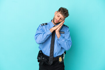 Young police blonde man isolated white on blue background making sleep gesture in dorable expression