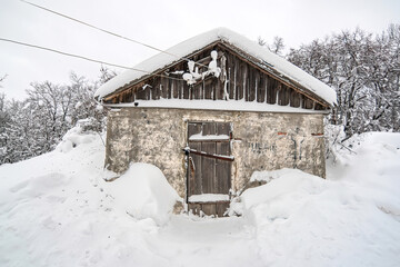 old grunge warehouse with scratched cement wall and locked wooden door under snow fall