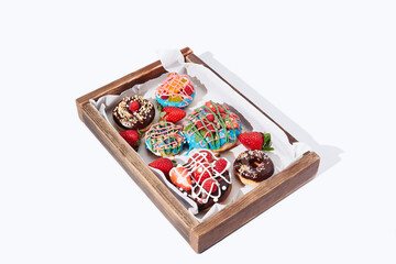 Decorated donuts with fruits in a box on white background