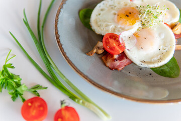 Scrambled eggs with bacon tomatoes and herbs on a white table