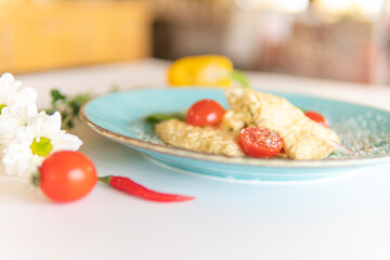 Scrambled eggs with bacon tomatoes and herbs on a white table
