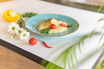 Scrambled eggs with bacon tomatoes and herbs on a white table