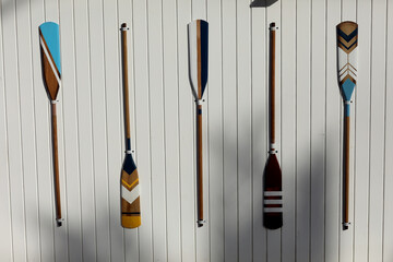 four colourful wooden paddles hangs on a white wall. canoe oars for active water sport. holiday...
