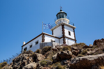 Fototapeta na wymiar Old lighthouse with Greece flag on blue sky background.