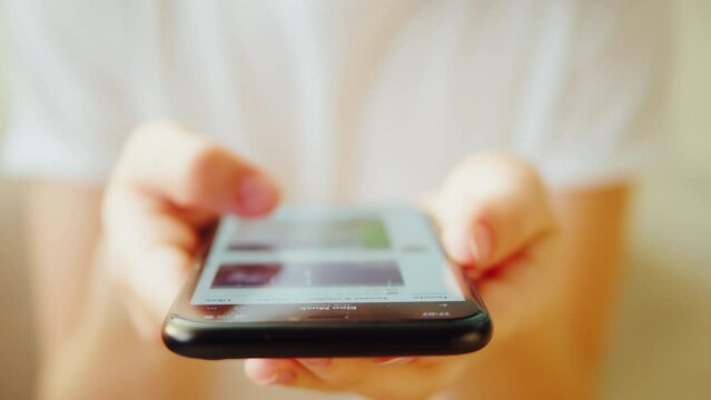 Using smartphone close-up. Young woman surfing the internet, networks and checking social media holding mobile phone.