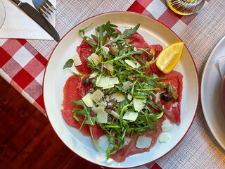 Beef carpaccio with arugula and lemon, top view