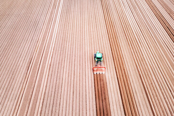 Lonely tractor on agricultural field with rows of plowed soil. Agricultural fields prepared for planting crops, topdown view. Industrial agriculture concept. Drone photography