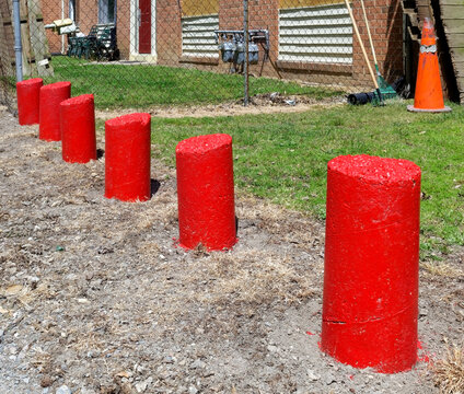 Bright red cement bollard deterrents to illegal parking.