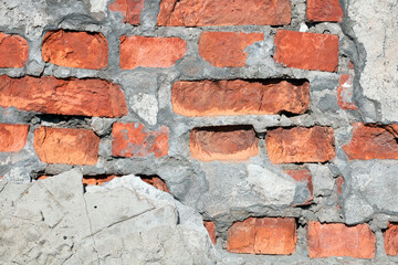 Ruined wall of a red brick building. Background of broken bricks.